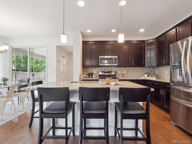15350 W 50th Dr, Golden, CO 80403 - kitchen featuring stainless steel appliances, decorative backsplash, pendant lighting, a sink, and a kitchen breakfast bar
