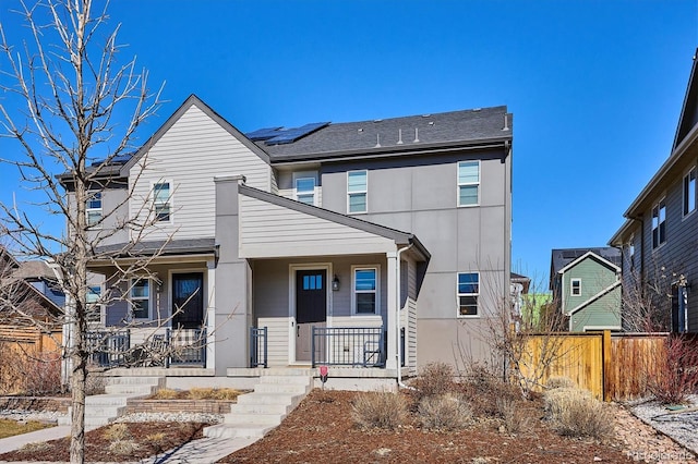 multi unit property with a porch, fence, and roof mounted solar panels