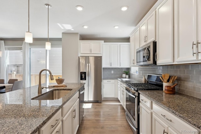 kitchen featuring white cabinetry, appliances with stainless steel finishes, a sink, and wood finished floors