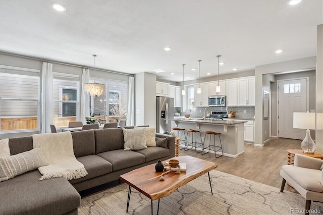 living room featuring a healthy amount of sunlight, light wood finished floors, a notable chandelier, and recessed lighting