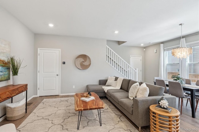 living area featuring recessed lighting, a notable chandelier, wood finished floors, baseboards, and stairs