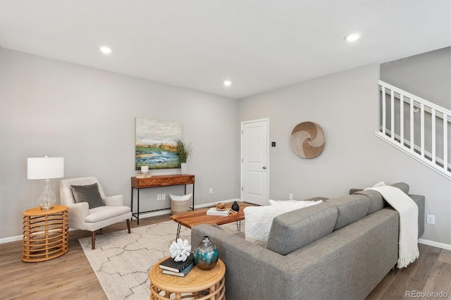 living room featuring stairs, baseboards, wood finished floors, and recessed lighting