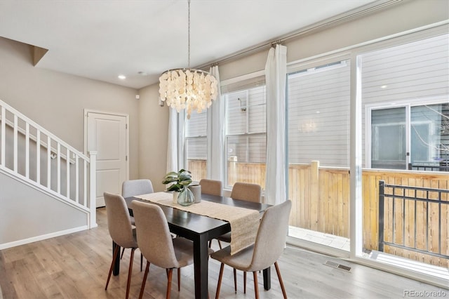 dining area with stairway, visible vents, wood finished floors, and an inviting chandelier