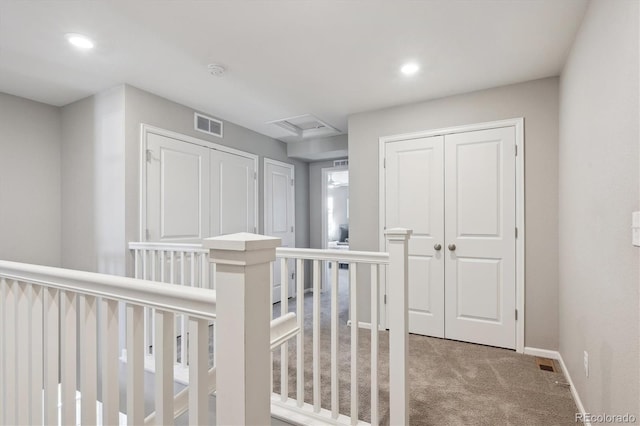 hall featuring recessed lighting, visible vents, attic access, light carpet, and baseboards