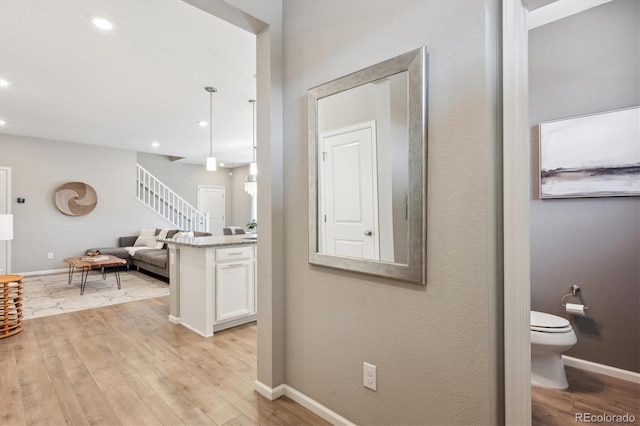 hall featuring light wood-type flooring, baseboards, and stairs