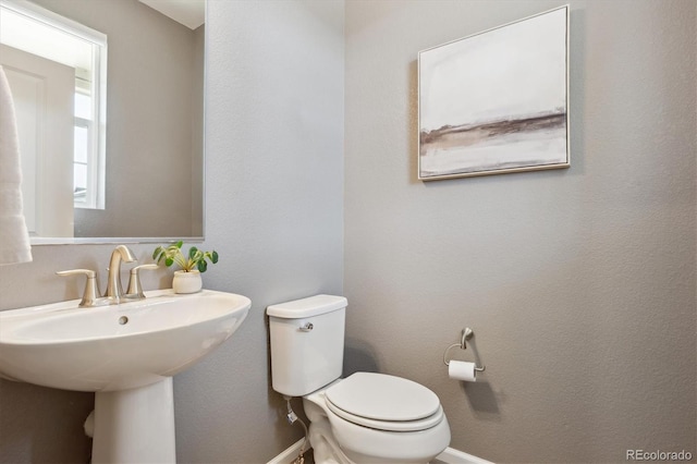 bathroom featuring baseboards, a sink, and toilet