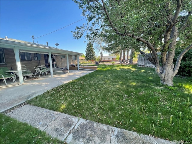 view of green lawn with a patio area
