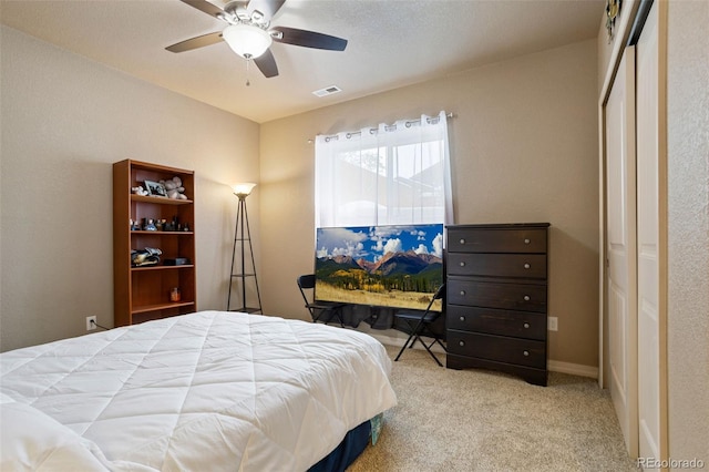 bedroom with ceiling fan, light colored carpet, and a closet