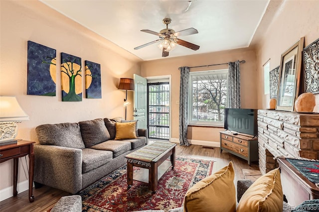 living room featuring wood finished floors, baseboards, and a ceiling fan