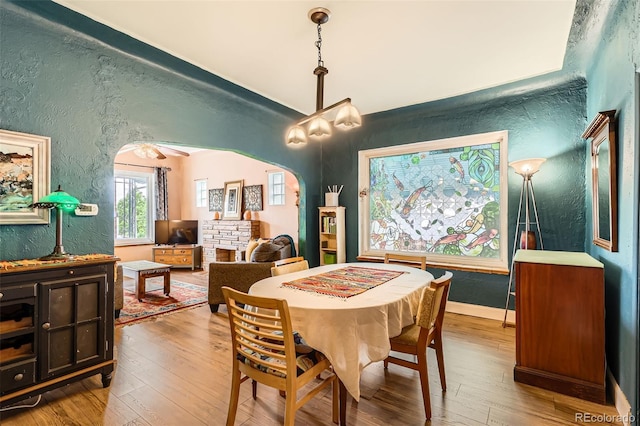 dining area featuring a textured wall, hardwood / wood-style flooring, and arched walkways