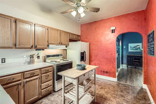 kitchen with white appliances, arched walkways, a ceiling fan, under cabinet range hood, and decorative backsplash