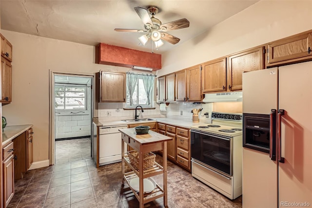 kitchen with white appliances, a sink, under cabinet range hood, ceiling fan, and plenty of natural light