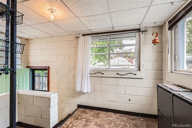 bathroom featuring concrete block wall and a drop ceiling
