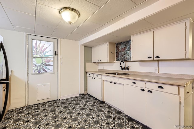 kitchen featuring a sink, white cabinetry, light countertops, and dark flooring