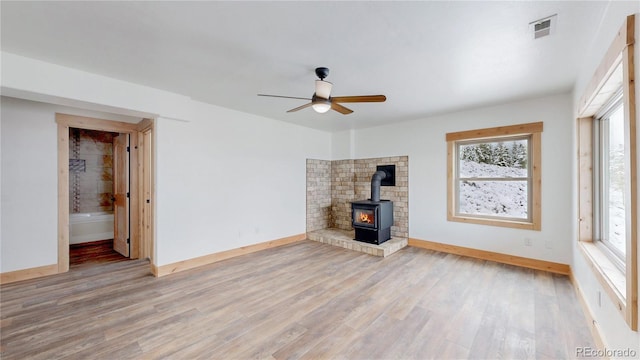 374 County Road 863, Tabernash, CO 80478 - unfurnished living room featuring a wood stove, a ceiling fan, healthy amount of natural light, and light wood-style flooring