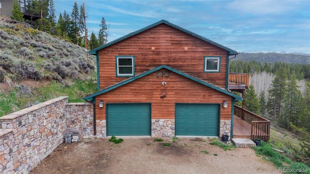 374 County Road 863, Tabernash, CO 80478 - view of side of home featuring stone siding, an attached garage, a view of trees, and dirt driveway