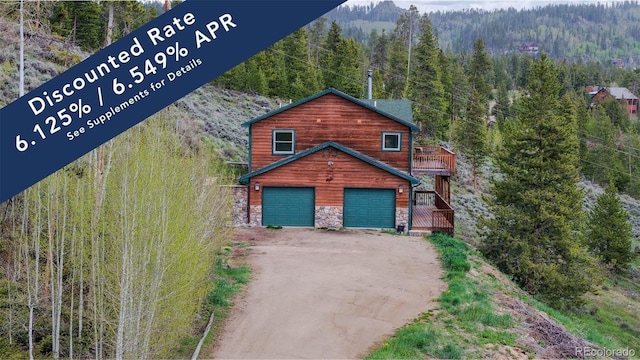 374 County Road 863, Tabernash, CO 80478 - chalet / cabin featuring a forest view, stone siding, an attached garage, and driveway
