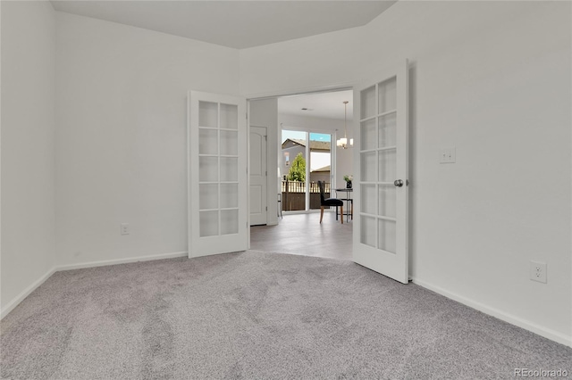 unfurnished room with carpet flooring, french doors, and a notable chandelier