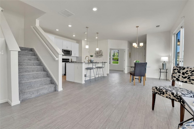 interior space with light wood-type flooring, a chandelier, and sink