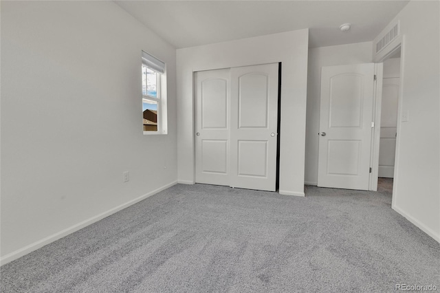 unfurnished bedroom with light colored carpet and a closet