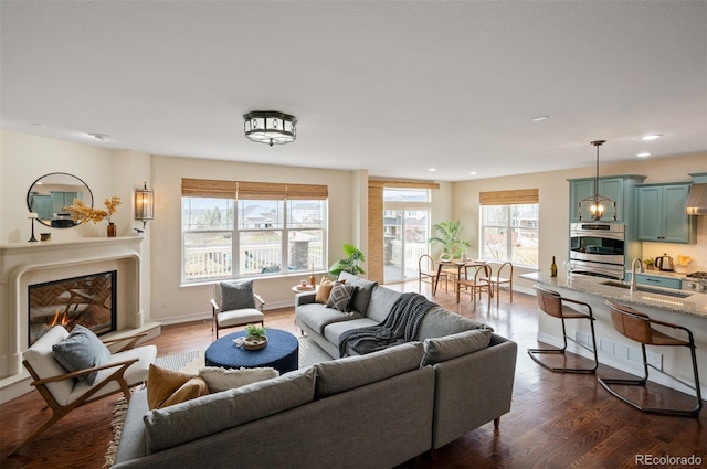 living room with a glass covered fireplace, recessed lighting, and dark wood-style flooring