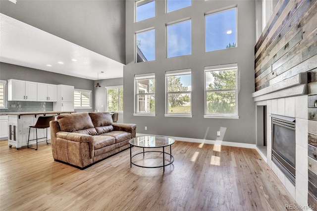 750 Deer Clover Cir, Castle Pines, CO 80108 - living area with light wood finished floors, a glass covered fireplace, a towering ceiling, and recessed lighting