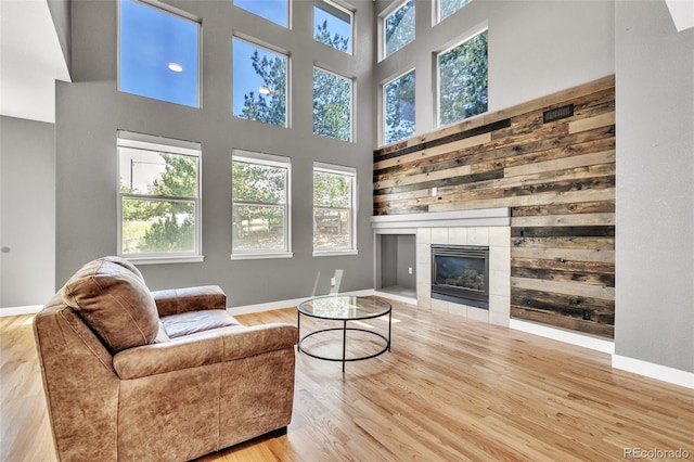 750 Deer Clover Cir, Castle Pines, CO 80108 - living area with wood finished floors, a tiled fireplace, and a high ceiling