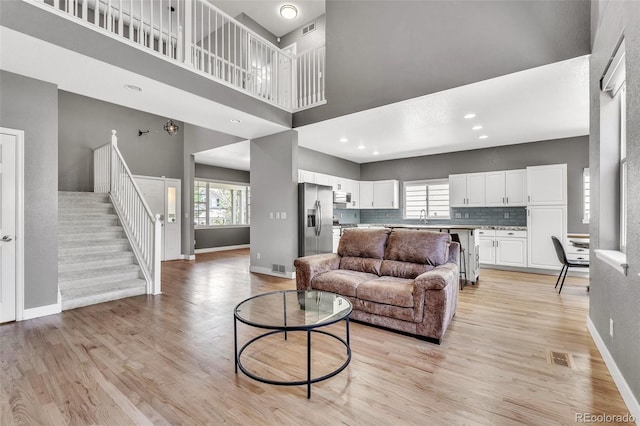750 Deer Clover Cir, Castle Pines, CO 80108 - living room featuring plenty of natural light, light wood-type flooring, a towering ceiling, stairway, and recessed lighting