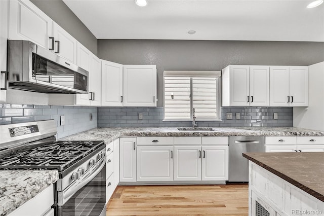 750 Deer Clover Cir, Castle Pines, CO 80108 - kitchen with stainless steel appliances, light wood-type flooring, white cabinetry, tasteful backsplash, and recessed lighting