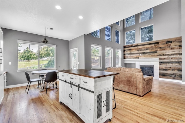 750 Deer Clover Cir, Castle Pines, CO 80108 - kitchen featuring butcher block countertops, light wood-type flooring, recessed lighting, white cabinetry, and a tile fireplace