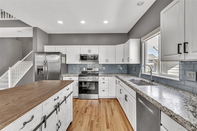 750 Deer Clover Cir, Castle Pines, CO 80108 - kitchen featuring stainless steel appliances, light wood-style flooring, white cabinetry, tasteful backsplash, and recessed lighting