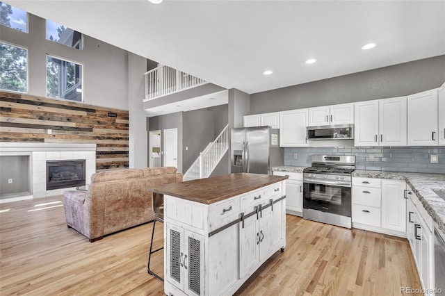 750 Deer Clover Cir, Castle Pines, CO 80108 - kitchen featuring stainless steel appliances, light wood finished floors, a towering ceiling, tasteful backsplash, and a breakfast bar area