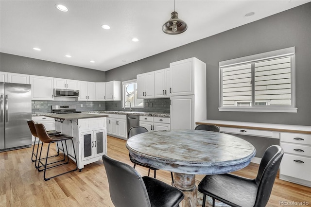 750 Deer Clover Cir, Castle Pines, CO 80108 - kitchen featuring appliances with stainless steel finishes, white cabinetry, a breakfast bar area, tasteful backsplash, and recessed lighting