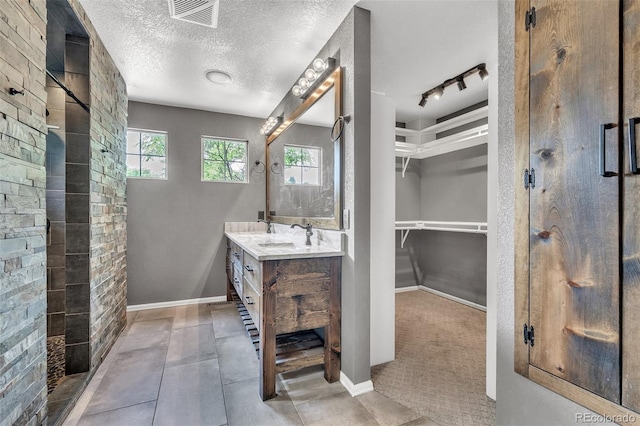 750 Deer Clover Cir, Castle Pines, CO 80108 - full bathroom with a shower stall, vanity, a spacious closet, a textured ceiling, and track lighting