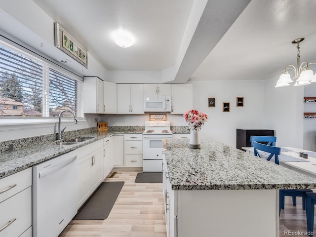 kitchen featuring a kitchen island, white appliances, white cabinetry, and a sink