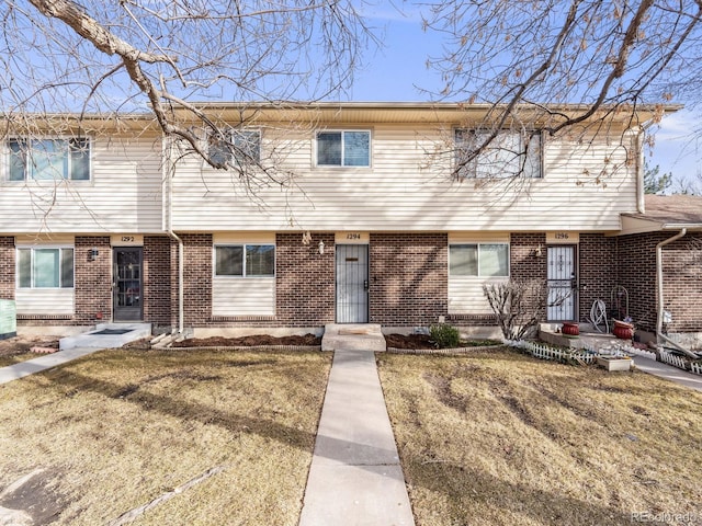 view of property with brick siding and a front yard