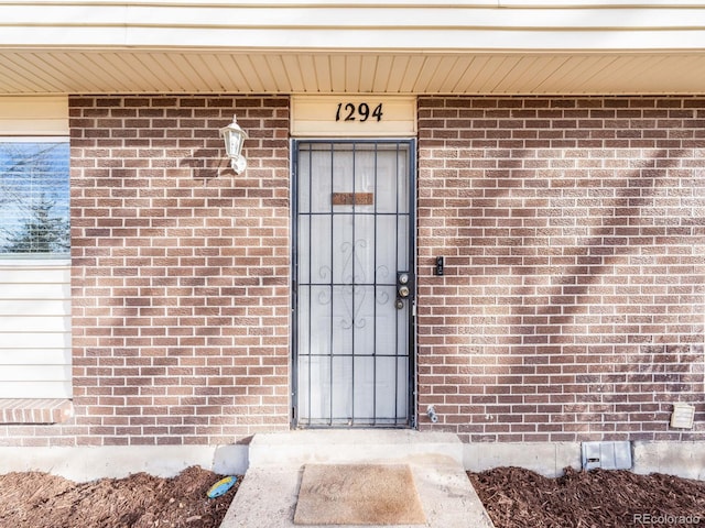 property entrance featuring brick siding and crawl space