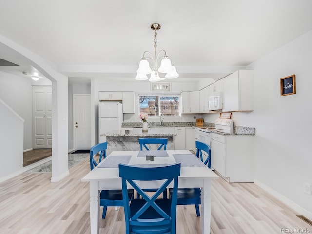 dining space featuring a notable chandelier, baseboards, visible vents, and light wood-style floors