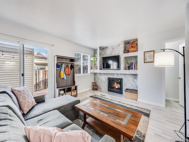 living area with baseboards, wood finished floors, and a high end fireplace