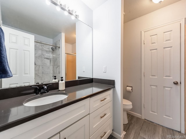 full bath with baseboards, toilet, wood finished floors, a tile shower, and vanity