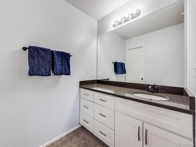 bathroom with a textured ceiling, vanity, and baseboards