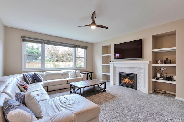 carpeted living area with ceiling fan, built in features, a wealth of natural light, and a tile fireplace