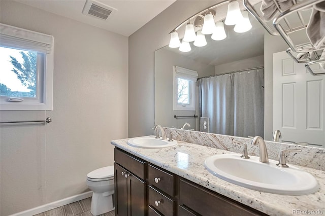 full bath featuring double vanity, toilet, visible vents, and a sink