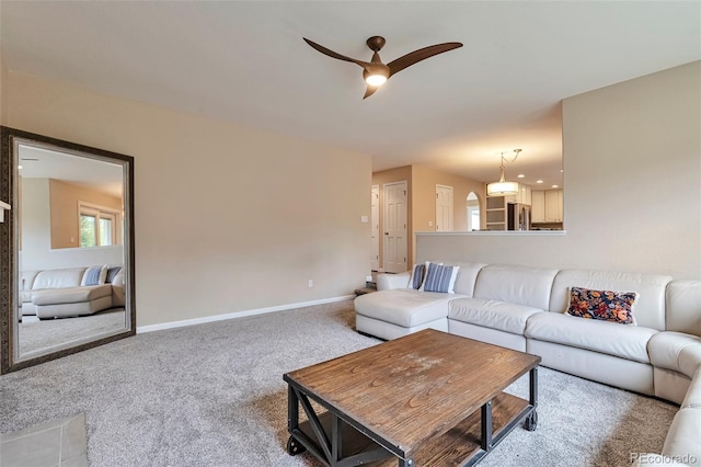 living area with carpet floors, baseboards, and ceiling fan