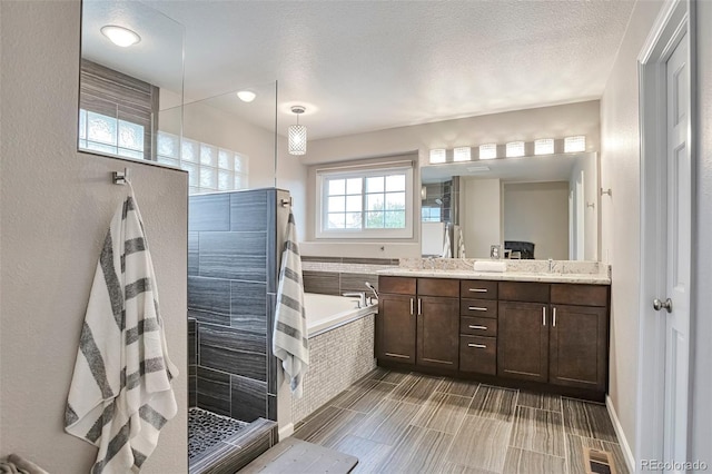 bathroom with double vanity, a garden tub, a textured ceiling, a sink, and a walk in shower