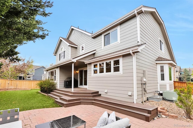 rear view of property with a lawn, a patio area, fence, and a wooden deck