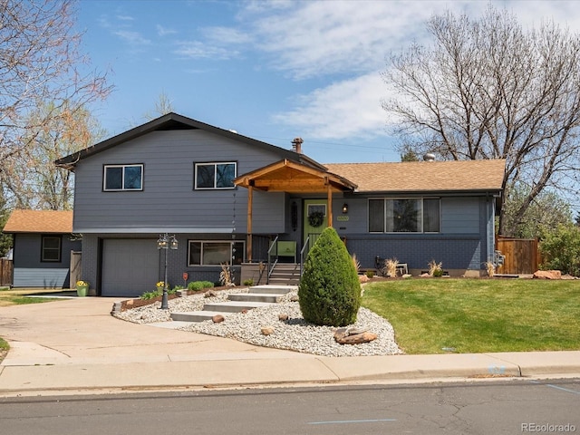 tri-level home featuring a garage, fence, a front yard, brick siding, and driveway
