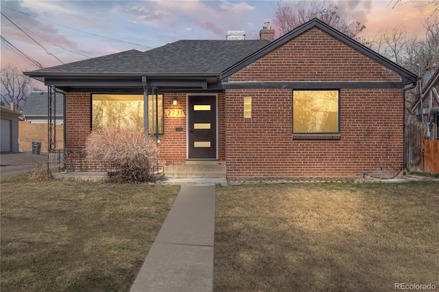 bungalow-style home featuring a front lawn, brick siding, and a chimney