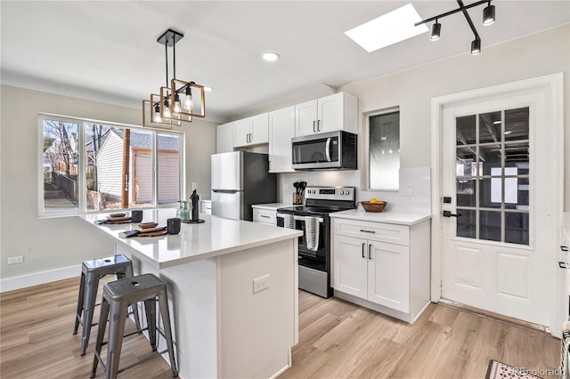 kitchen with stainless steel appliances, a kitchen island, a breakfast bar area, and white cabinets