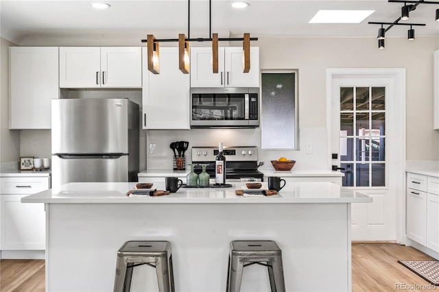 kitchen featuring white cabinetry, appliances with stainless steel finishes, a kitchen island, and light countertops